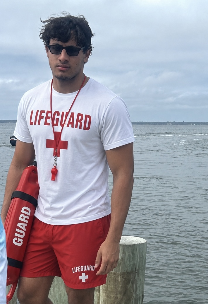 Ryan, certified lifeguard, standing by the water with a rescue tube